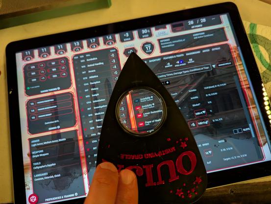 A web browser in a tablet showing a Dungeons & Dragons character sheet with a ouija board puck positioned over the spell Lesser Restoration, my fingers still on the puck in the position used to commune.