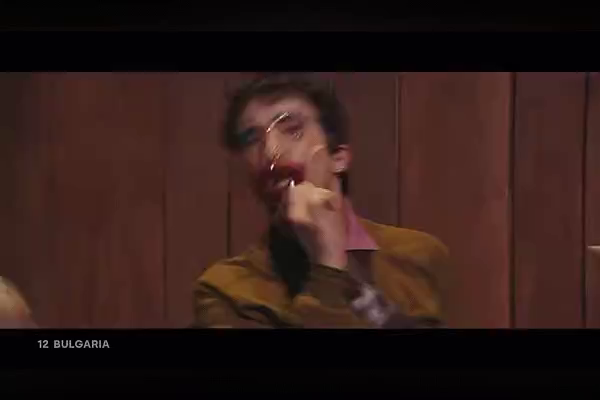 A slow pan of four people mechanically and aggressively smearing lipstick all around their mouths against a background vertical wood paneling; each person is wearing a transparent mask with smeared and giant eye shadow and lipstick.