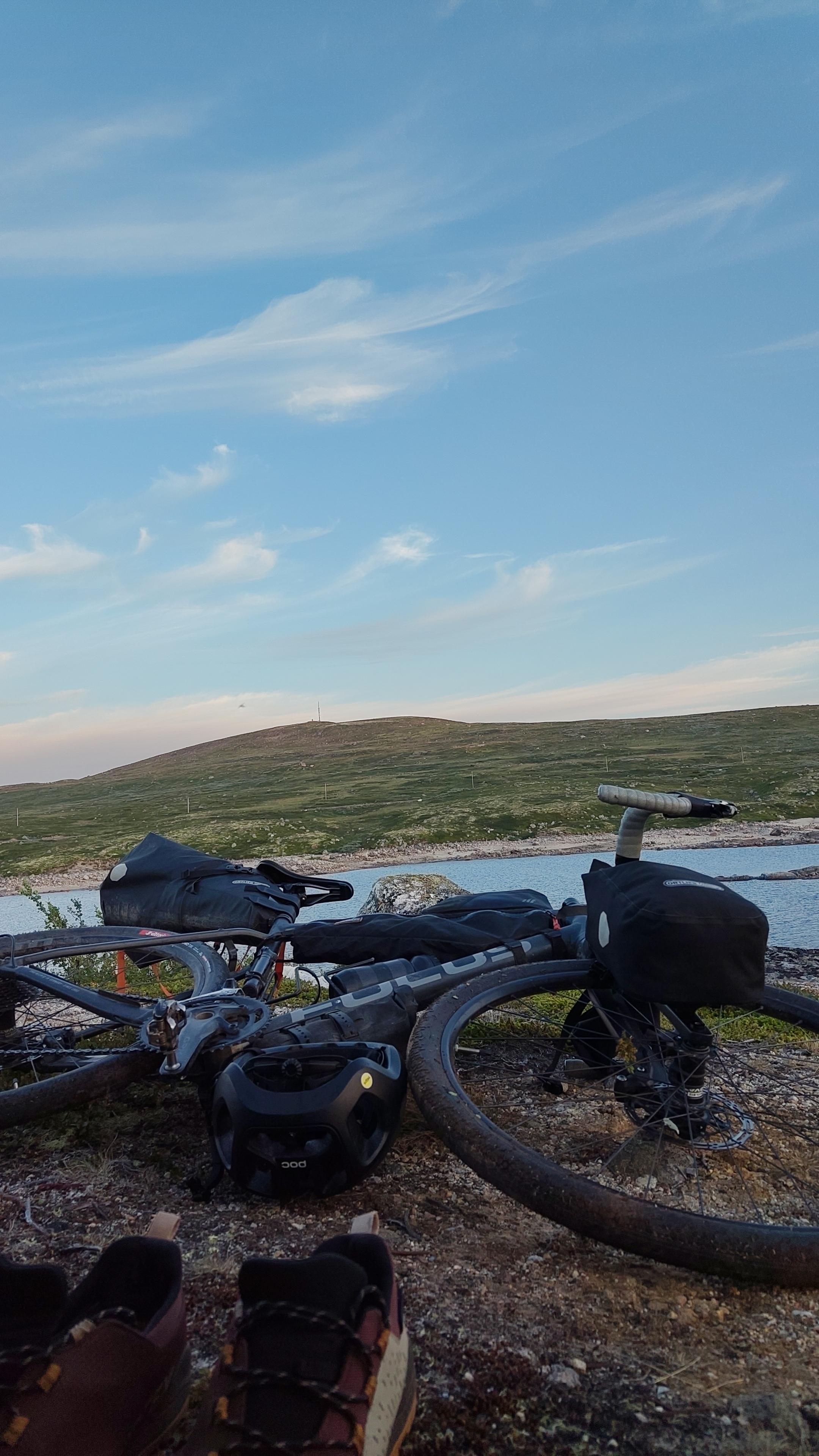Gravel bicycle on the side on the ground, lake in the background.