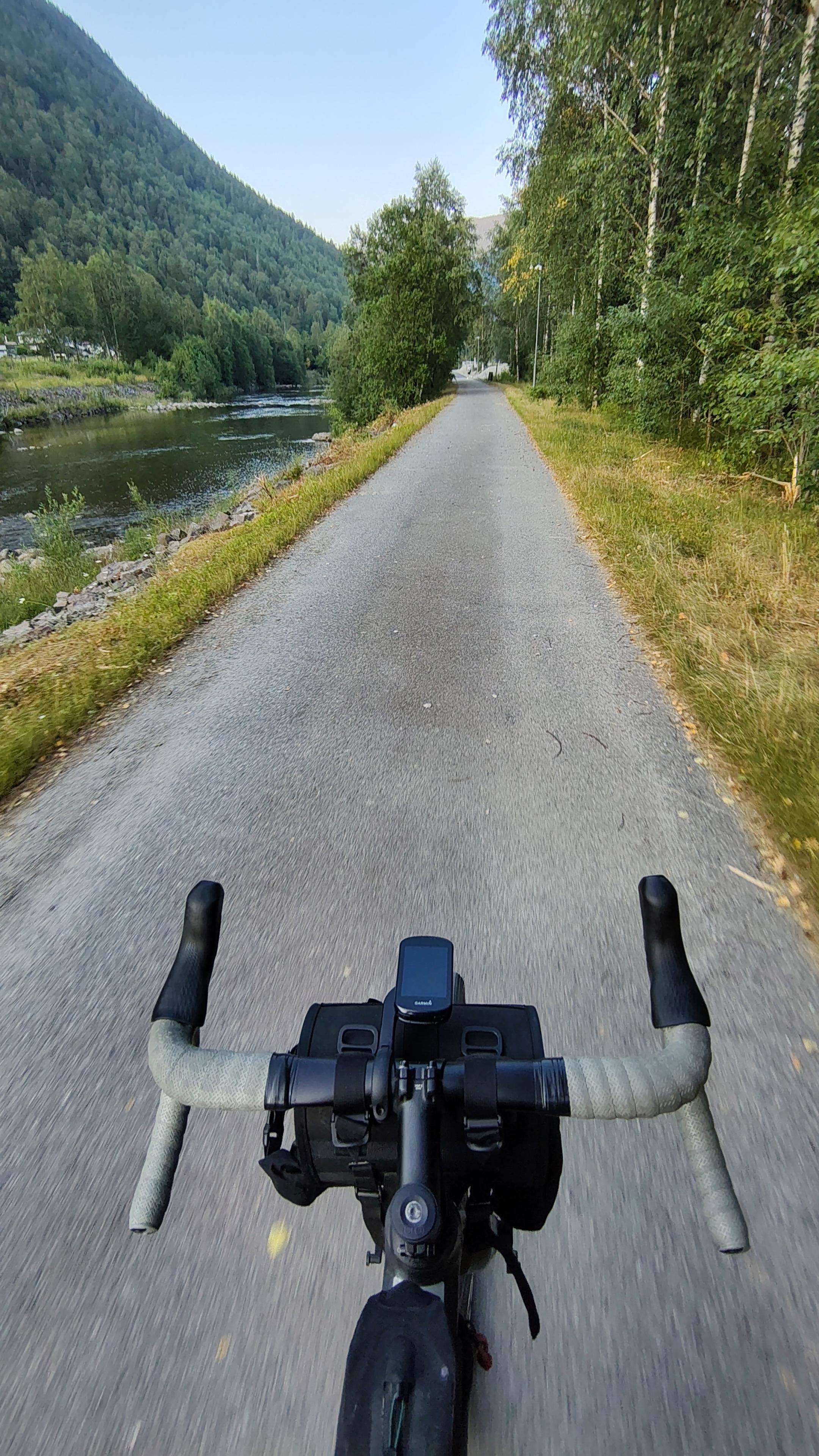 Handlebar of a bicycle on gravel road, river on the left side.