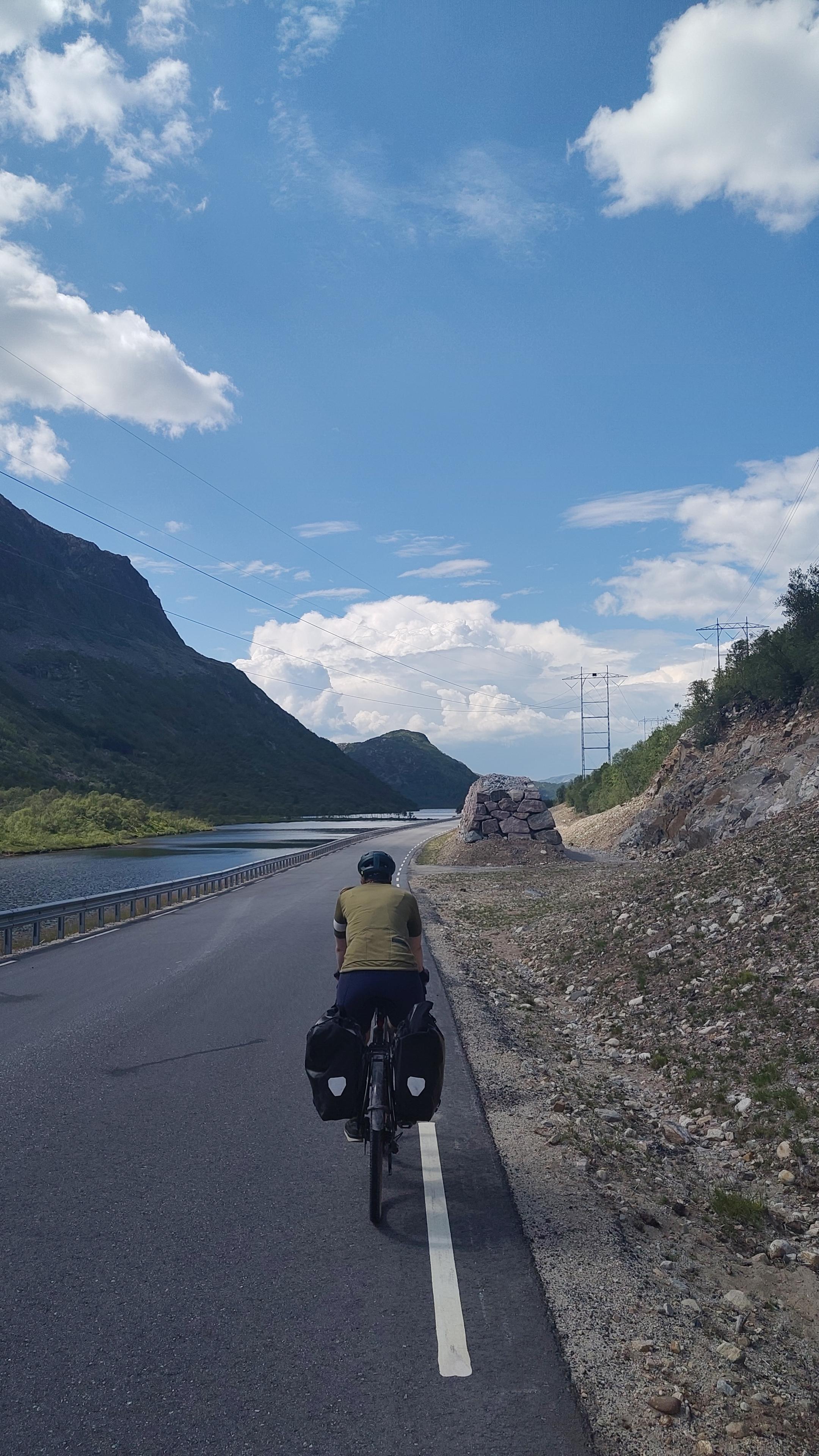 Cyclist in a valley, lake on the left side.